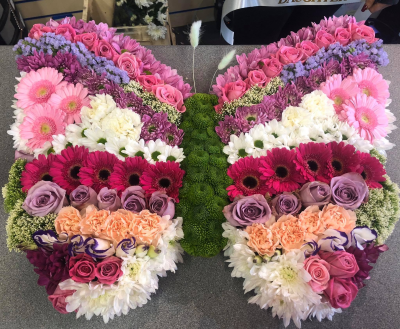 Butterfly - A stunning butterfly-shaped funeral tribute designed to symbolise transformation, hope, and the enduring beauty of cherished memories. Created in a harmonious blend of soft pinks, lilacs, whites, and deeper accent tones, this exquisite arrangement offers a heartfelt expression of love, comfort, and remembrance.

The butterfly design represents a gentle journey, making it a meaningful choice for celebrating a life that touched many hearts. Expertly handcrafted with fresh seasonal blooms and foliage, this elegant tribute provides a beautiful focal point at funeral services, memorial ceremonies, or celebrations of life.