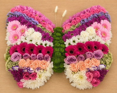 Butterfly - A stunning butterfly-shaped funeral tribute designed to symbolise transformation, hope, and the enduring beauty of cherished memories. Created in a harmonious blend of soft pinks, lilacs, whites, and deeper accent tones, this exquisite arrangement offers a heartfelt expression of love, comfort, and remembrance.

The butterfly design represents a gentle journey, making it a meaningful choice for celebrating a life that touched many hearts. Expertly handcrafted with fresh seasonal blooms and foliage, this elegant tribute provides a beautiful focal point at funeral services, memorial ceremonies, or celebrations of life.